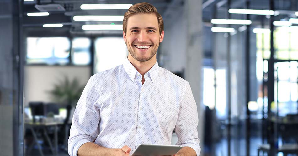 Homem sorrindo segurando um tablet com tipos de alopecia